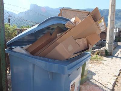 Un contenidor blau amb restes de paper i cartró al seu interior.