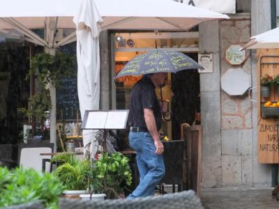 Un turista es refugia davall un paraigües