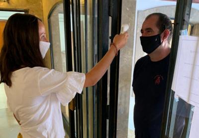 Mirant la temperatura a una persona que vol entrar a l'edifici.