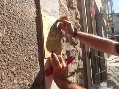 Operaris col.locant una placa daurada, avui